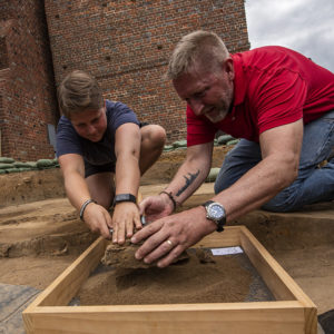 Staff Archaeologist Caitlin Delmas and Senior Conservator Dan Gamble place brigandine armor in a screen for transport to the lab.