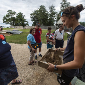 Site Supervisor Anna Shackelford shares the just-excavated matchlock lock with visitors.