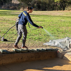 Site Supervisor applies water to excavations to make the features stand out for the photographs.