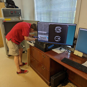 Archaeological Conservator Don Warmke prepares several sword pommels for an X-ray scan. His prior shot of two rapier hilts can be see on the screen.