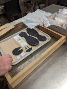 Senior Conservator Dr. Chris Wilkins examines some of the shoe leather found in the Governor's Well. He is closely monitoring these artifacts during their slow-drying process.