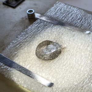 A silver English sixpence being retreated by Senior Conservator Dan Gamble.