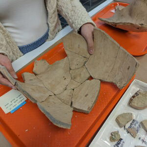 Curatorial Intern Amanda Nedell holds a partial Spanish olive jar that she is mending.