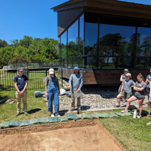 A field school student explains the excavations in his square to staff and other students.