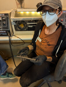 Field school student Kristin Grossi holds a spike from the gun platform of Confederate Fort Pocahontas. She has just completed removing corrosion from the spike using air abrasion.