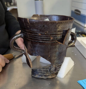 Assistant Conservator Jo Hoppe is preparing an Essex post-medieval blackware posset pot for additional mending.