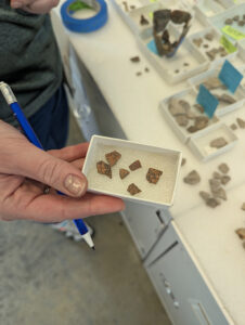 Senior Curator Leah Stricker holds crucible sherds that are likely part of the same vessel but can't be deemed so with certainty because they don't mend together.