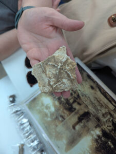 Assistant Curator Lauren Stephens holds a piece of interior plaster from the 1617 church. This side would have adhered to the church's wooden frame, with the protruding "X" evidencing scoring in the wood meant to help the plaster stay put.