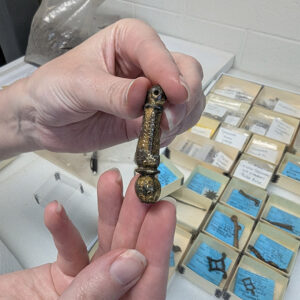 An ornate neck of a copper alloy spur including the rowel box where the rowel connects