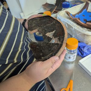 Assistant Conservator Jo Hoppe holds the base of a Midlands purple butter pot that she's conserving.