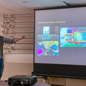 Man presenting and gesturing to images on a projected slide