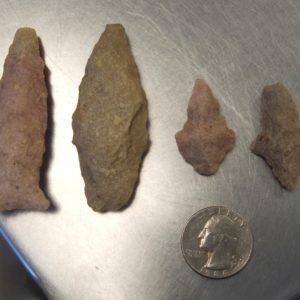 Projectile points next to a quarter for scale