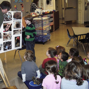 man and boy presenting a poster to a group of children