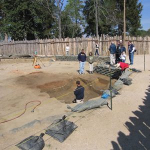 Visitors watch archaeologist working in excavation unit