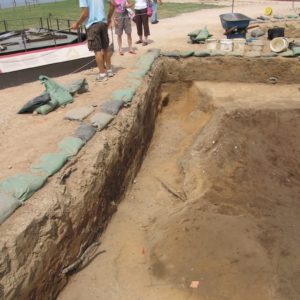 Four people standing near excavation unit lined with sandbags