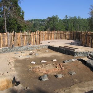 Excavation unit lined with sandbags in front of a palisade