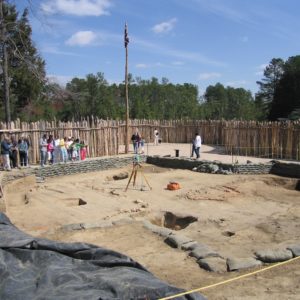 Group looks at excavations in front of a palisade