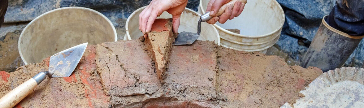 A person removes a wedge-shaped brick from the brick well ring