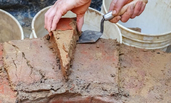 A person removes a wedge-shaped brick from the brick well ring