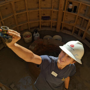 Site Supervisor Anna Shackelford hands a case bottle fragment to one of the archaeologists at the surface.