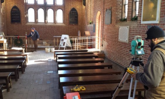 Archaeologist recording with total station in brick church