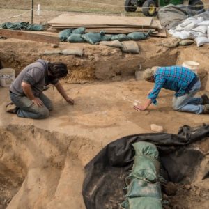 Archaeaologists excavating in unit lined with sandbags