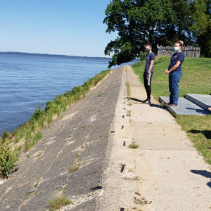 Archaeologists standing on a slanting wall by a riverbank