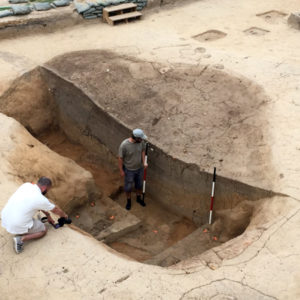 Archaeologists recording stratigraphic layers in excavation unit walls