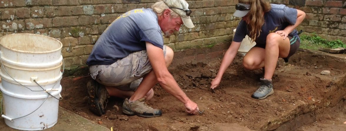 Archaeologists excavating by a brick church