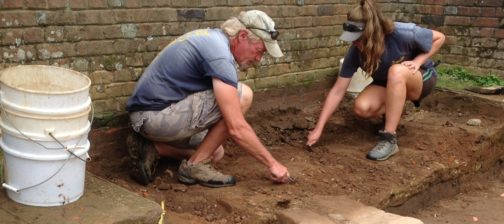 Archaeologists excavating by a brick church