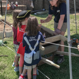 Woman shows children artifact from screen