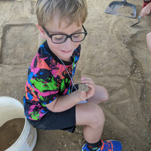 A camper holds a piece of a brick with the initials "RF." This is one of several such bricks in the Jamestown Rediscovery collection.