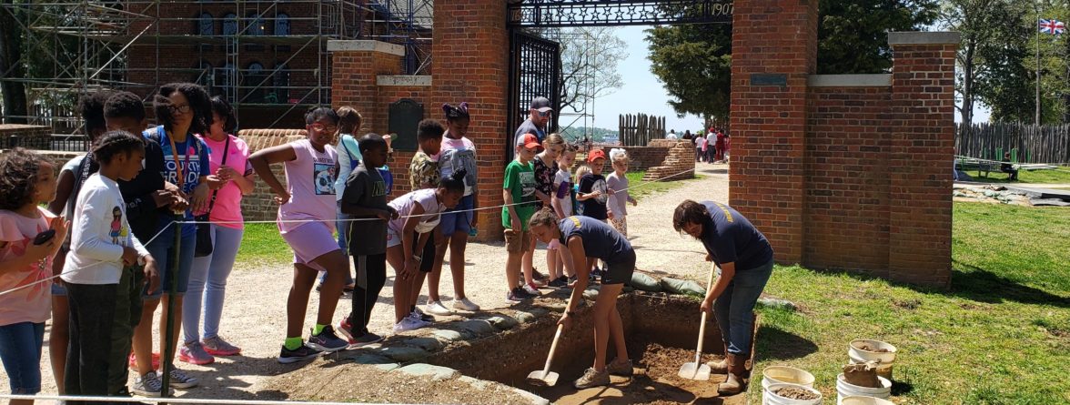 Children watch archaeologists shovel