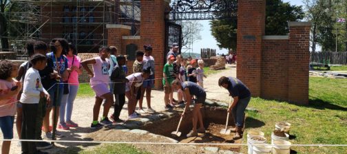 Children watch archaeologists shovel