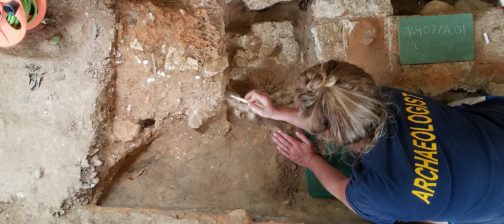 Archaeologist excavating floor features