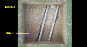 A drone shot of one of the Smithfield excavation squares. The utility pipes (1930s) and network cables (2000s) were spared damage thanks to the careful work of the archaeology team. Two ditches' borders are highlighted. These previously unknown features don't line up with any known property boundaries.