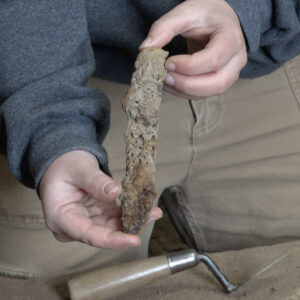 Staff Archaeologist Caitlin Delmas holds the knife blade she excavated from the fort's eastern palisade wall.